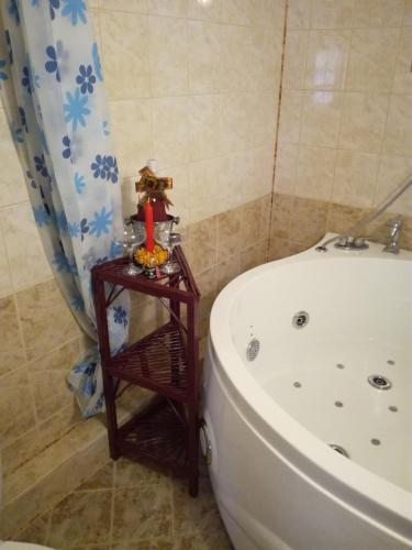 a bathroom with a bath tub and a table next to a bath tub at Hadjibulevata Guest House in Kovachevtsi