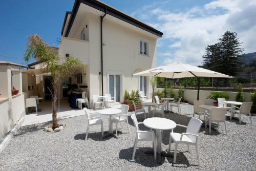 eine Terrasse mit Tischen, Stühlen und einem Sonnenschirm in der Unterkunft Residenza Porta Romana in Tropea