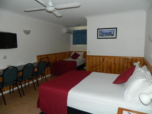 a hotel room with a bed and a table and chairs at Twin Towns Motel in Tweed Heads