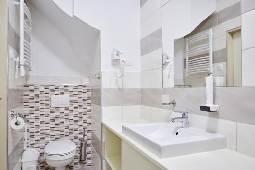 a white bathroom with a sink and a toilet at Hotel Astoria in Balatonfüred
