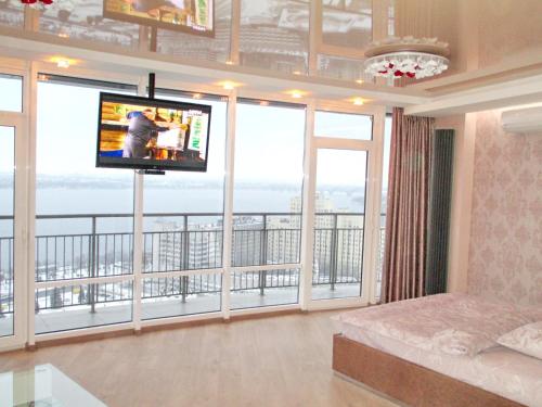 a living room with a television and large windows at Most City Apart-Hotel in Dnipro