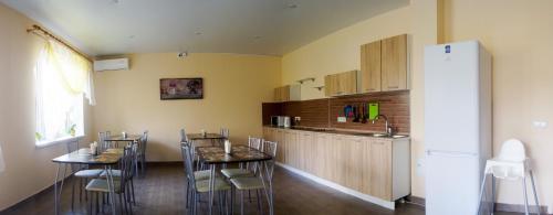 a kitchen with two tables and a refrigerator at Rodnoy Prichal Guest House in Arkhipo-Osipovka