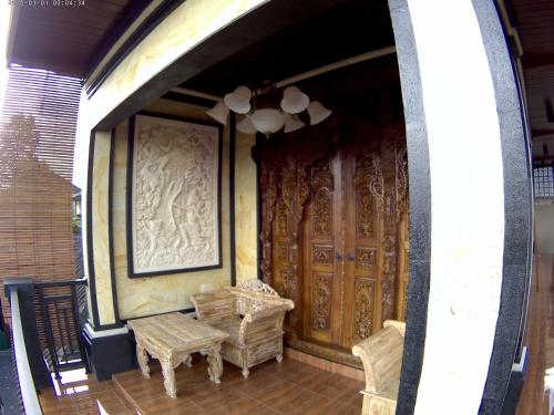 a porch with a pair of wicker chairs and a wooden door at Indy House in Ubud