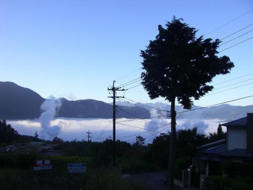 a view of a foggy mountain range with a tree at Yufuin Country Road Youth Hostel in Yufuin