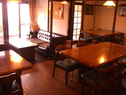 a restaurant with wooden tables and chairs and a couch at Yufuin Country Road Youth Hostel in Yufuin