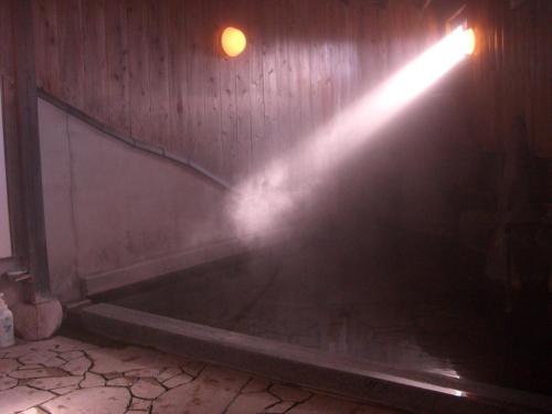 a beam of light in a room with a tub at Yufuin Country Road Youth Hostel in Yufuin