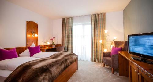 a hotel room with a bed and a flat screen tv at Landhotel Schneider in Riedenburg