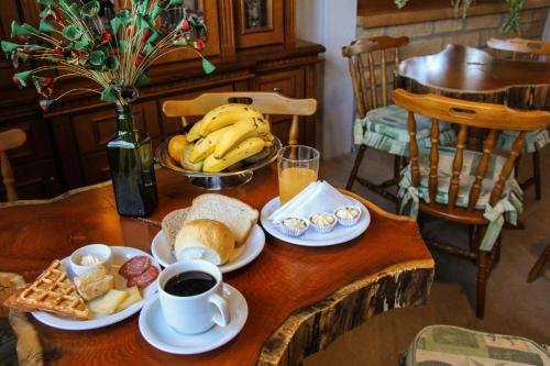 a table with breakfast foods and coffee and bananas on it at Hotel Aconchego da Serra in Gramado