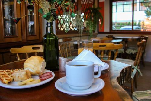 a table with a cup of coffee and a plate of food at Hotel Aconchego da Serra in Gramado