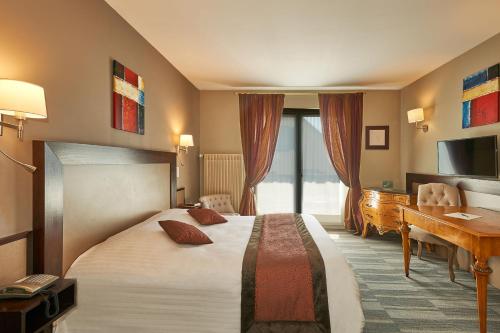 a hotel room with a large bed and a desk at Parc Hôtel in Wangenbourg