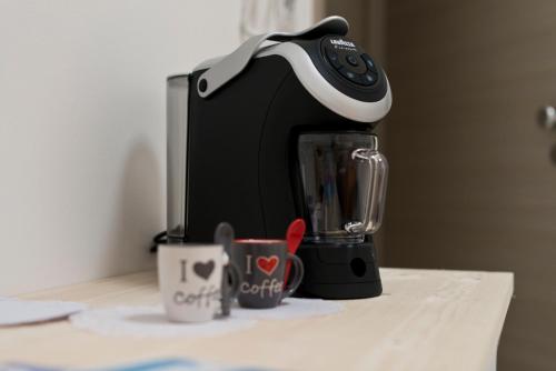 a black coffee maker sitting on a counter with two cups at TornaRé in Trani