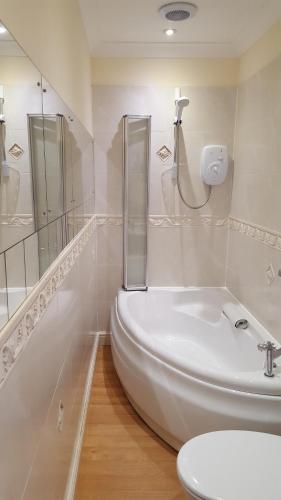 baño blanco con ducha y lavamanos en Cotswold House en Falmouth