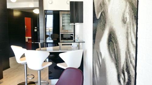 a kitchen with white chairs and a table at Most City Apart-Hotel in Dnipro