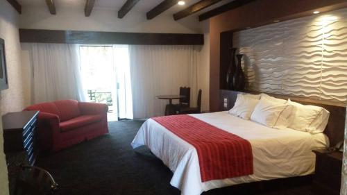 a hotel room with a bed and a red chair at Radisson Hotel Tapatio Guadalajara Aeropuerto in Guadalajara