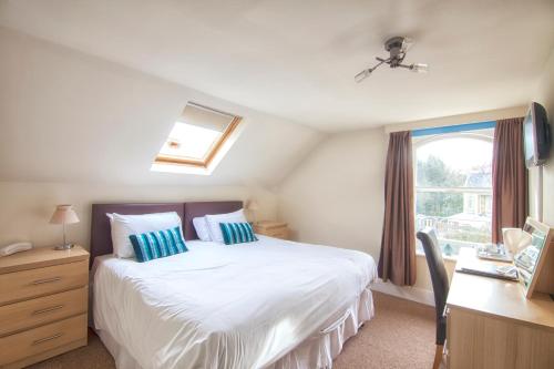 a bedroom with a bed and a desk and a window at Luccombe Manor Country House Hotel in Shanklin