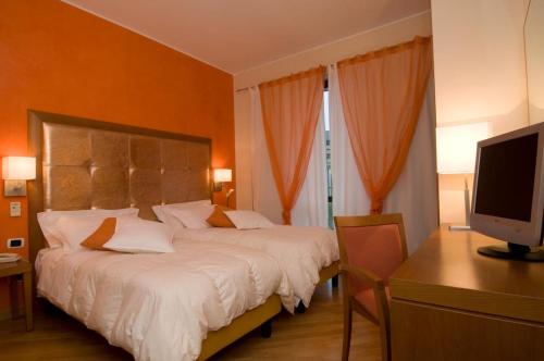 a bedroom with a bed and a desk with a television at Hotel Europa in Padova
