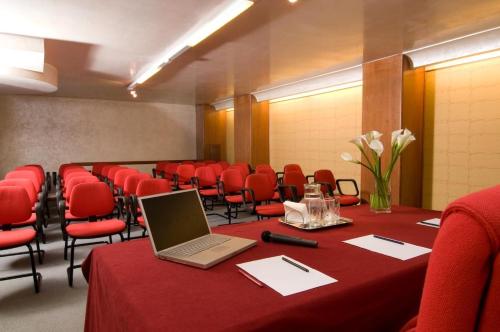 a conference room with a laptop on a table and red chairs at Hotel Europa in Padova