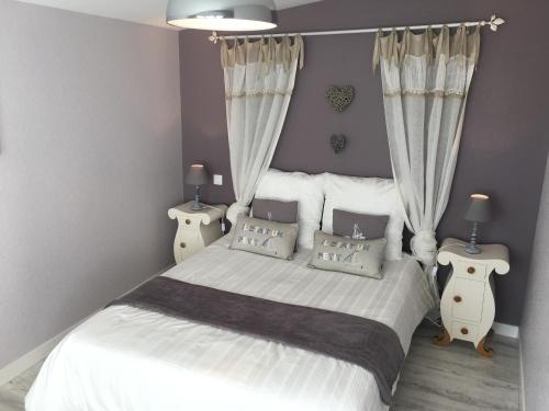 um quarto com uma grande cama branca com cortinas em Mes Ptits Apparts em La Cotinière