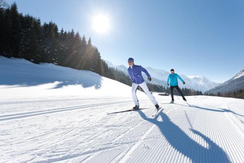 two people are skiing down a snow covered slope at Gästehaus Kristall in Kleinarl