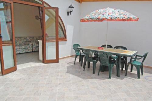 a table and chairs with an umbrella in a room at Mare Blu in Gioiosa Marea