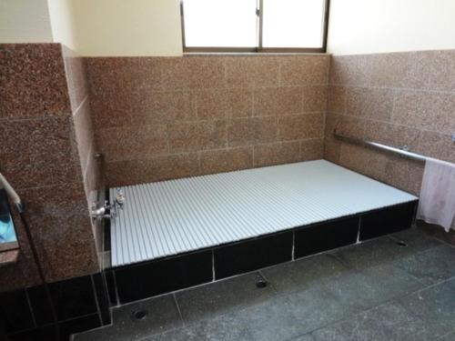 a shower stall with a bench in a bathroom at Minshuku Kobayashi in Narusawa