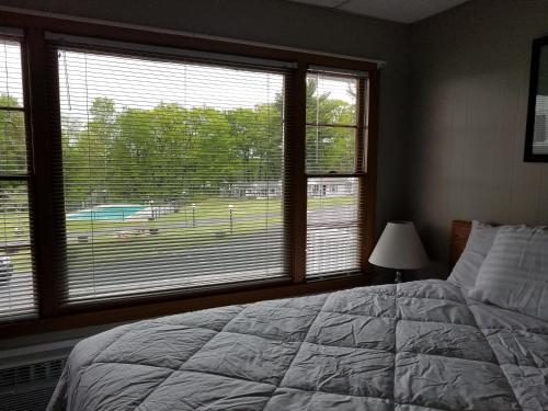 a bedroom with a bed and two large windows at Grand View Resort in Weirs Beach