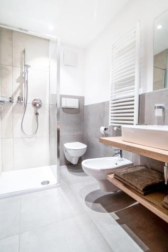 a bathroom with a shower and a toilet and a sink at Hotel Sonnenheim in Vipiteno