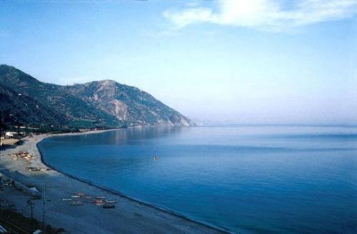a view of a beach with mountains in the distance at Mare Blu in Gioiosa Marea