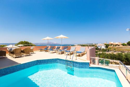 a pool with chairs and umbrellas on a roof at Leste Luxury Homes in Plaka