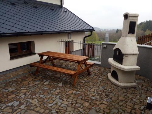 a wooden bench sitting on a patio with a house at Haus Tolštejn in Jiřetín pod Jedlovou