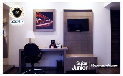 a room with a desk and a tv and a chair at Hotel Mansur Business & Leisure in Córdoba
