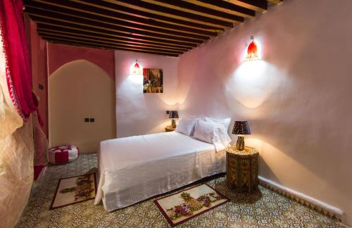 um quarto com uma cama branca e 2 candeeiros em Riad Diwan em Fez