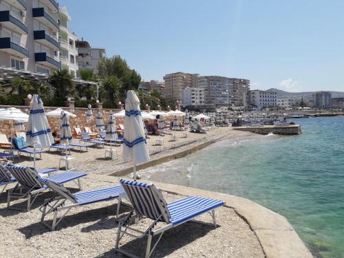 a group of chairs and umbrellas on a beach at Olive Tree Apartment in Sarandë