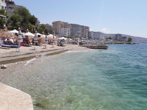 a beach with chairs and umbrellas and the water at Olive Tree Apartment in Sarandë