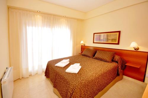 a bedroom with a bed with two towels on it at Orion Apartamentos in Bahía Blanca