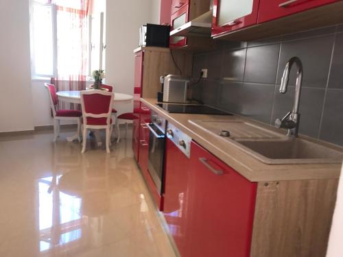 a kitchen with red cabinets and a sink and a table at Pula Antic Rooms in Center in Pula