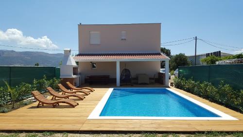 a backyard with a pool and chairs and a house at Villa Perlla in Split