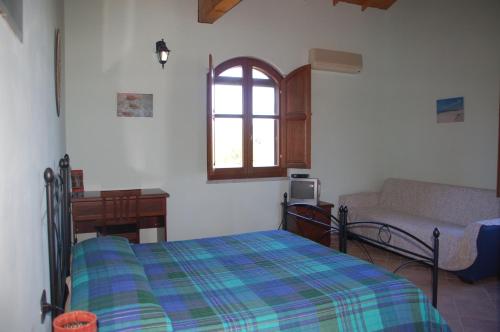 a bedroom with a bed and a couch and a window at B&B Nuraximannu in Santadi