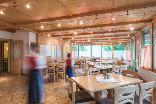 a person walking through a restaurant with tables and chairs at Pension Bäuerle in Heiligenblut