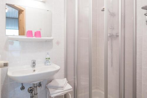 biała łazienka z umywalką i prysznicem w obiekcie Pension Bäuerle w mieście Heiligenblut