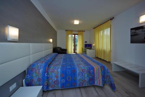 a bedroom with a large bed with a blue bedspread at Park Hotel Val Di Monte ***S in Malcesine