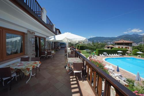 a balcony with tables and chairs and a swimming pool at Park Hotel Val Di Monte ***S in Malcesine