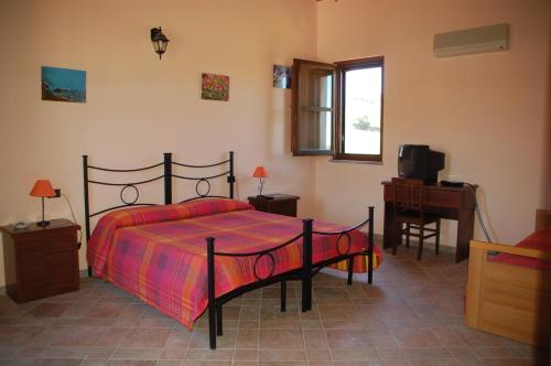 a bedroom with a bed and a desk and a television at B&B Nuraximannu in Santadi