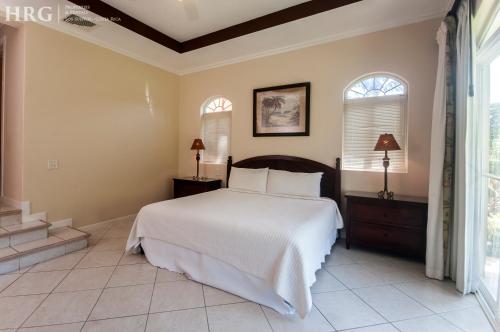 a bedroom with a large bed and two windows at HRG Condos at Los Sueños in Jacó