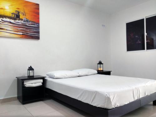 a bedroom with a bed with two night stands and two lamps at Hotel El Emigrante in Puerto Colombia