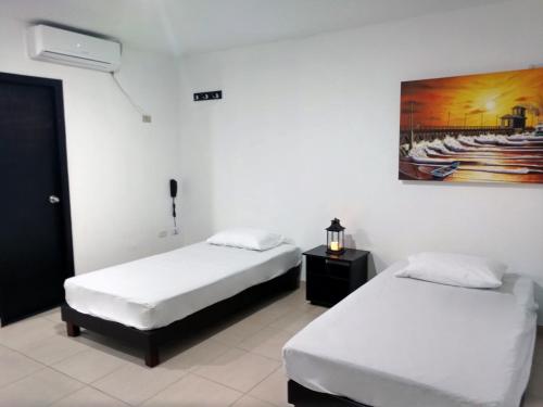 a room with two beds and a painting on the wall at Hotel El Emigrante in Puerto Colombia