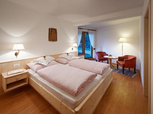 サンタ・クリスティーナ・ヴァルガルデーナにあるApartment Albertのベッドルーム1室(大型ベッド1台、赤い椅子付)