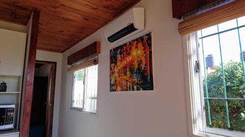 a painting on a wall next to a window at Cabañas 57 in Villa Carlos Paz