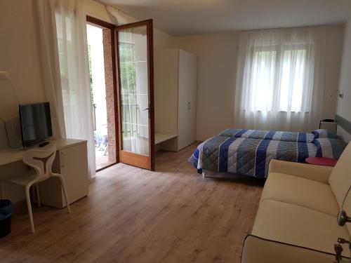 a bedroom with a bed and a tv and a couch at Park Hotel Val Di Monte ***S in Malcesine