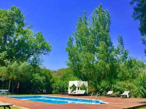 a swimming pool with a table and chairs and trees at Hotel Masia La Palma in Espinavesa